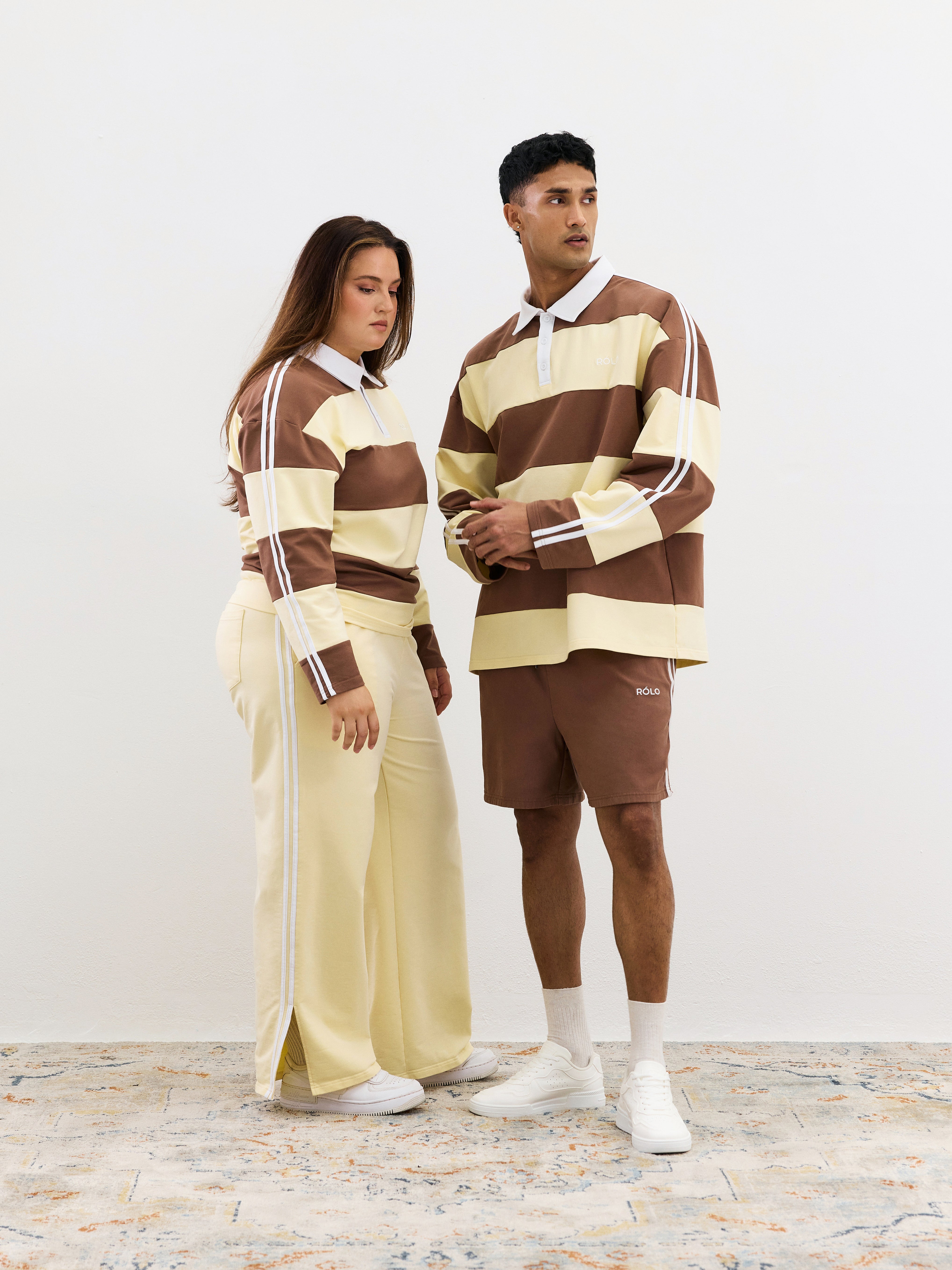 Two people wearing matching brown and beige striped outfits on a white background