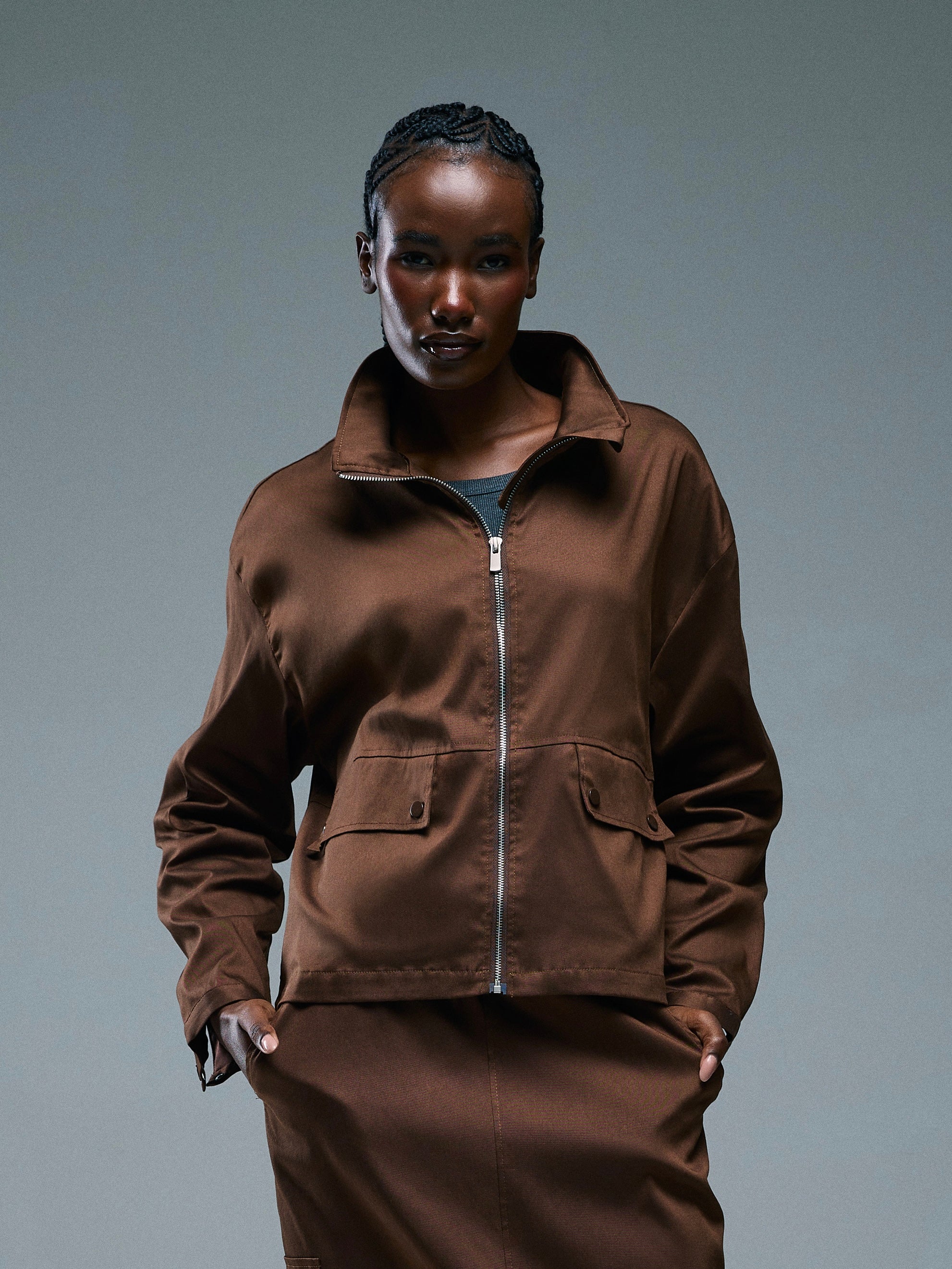 Person wearing a brown jacket  from RÓLO and pants against a gray background