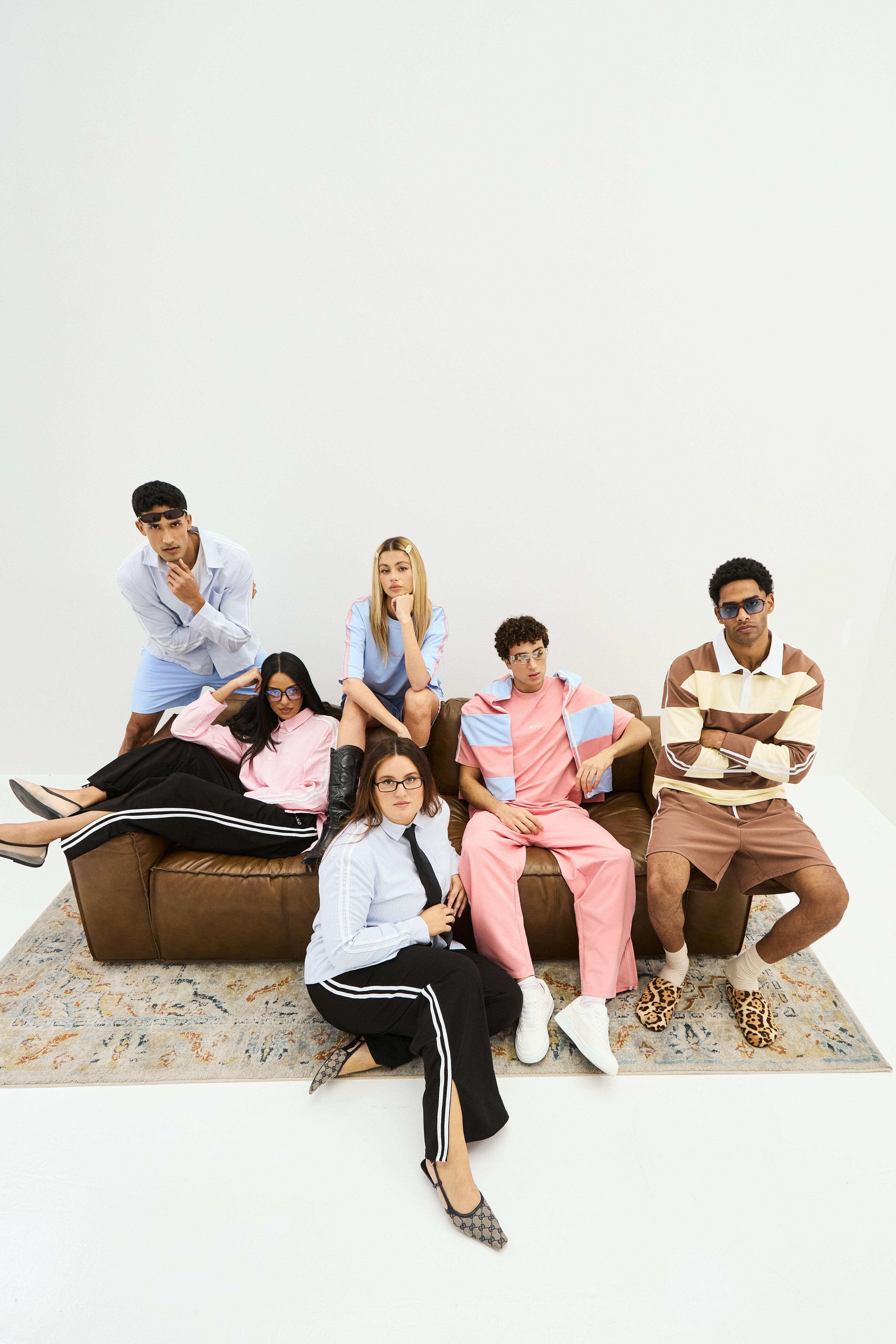 Group of people sitting on a brown couch in a minimalistic setting wearing rolo brand