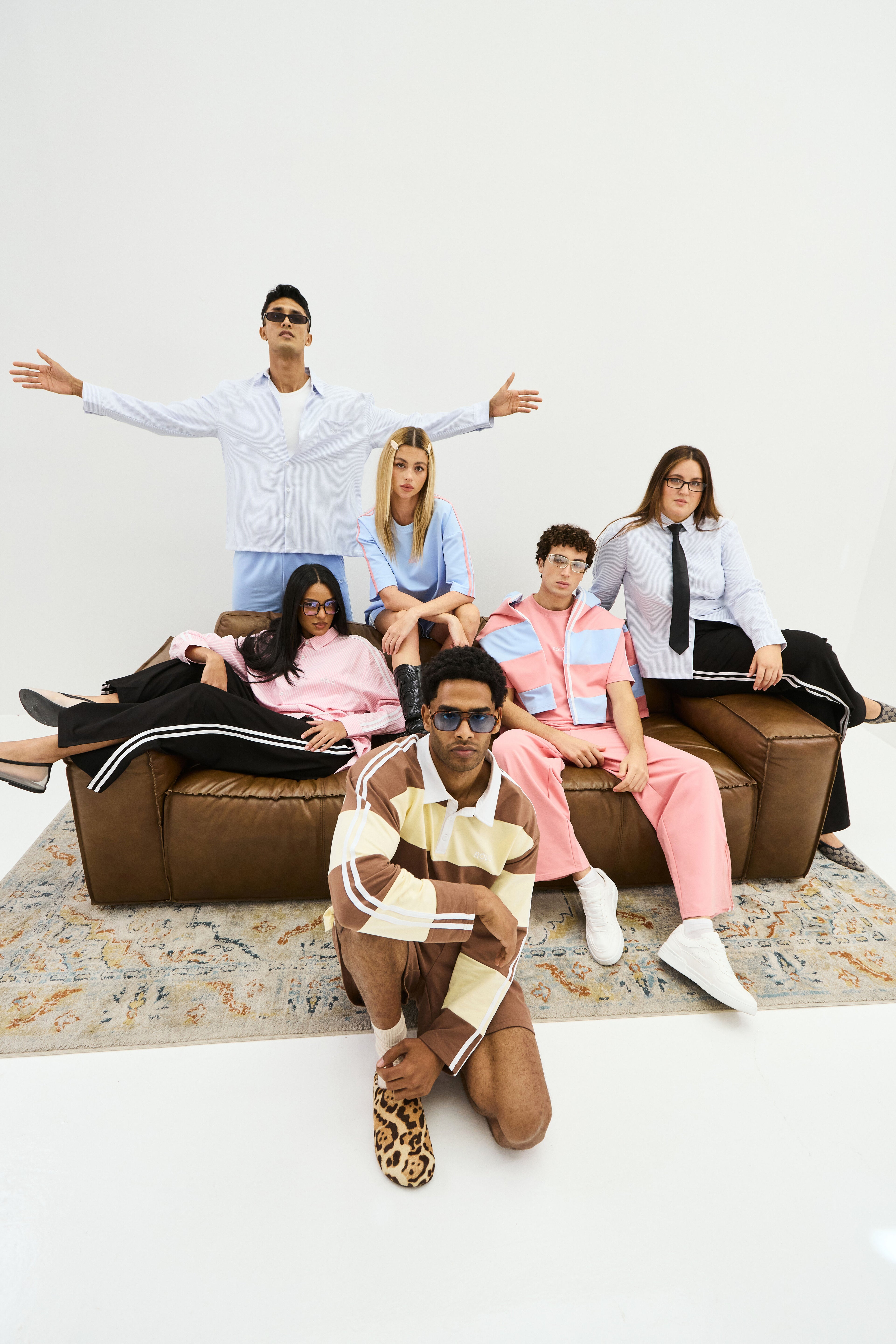 Group of people posing on a brown couch against a white wall wearing rolo brand